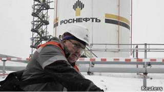 Работник "Роснефти" закручивает вентель 
